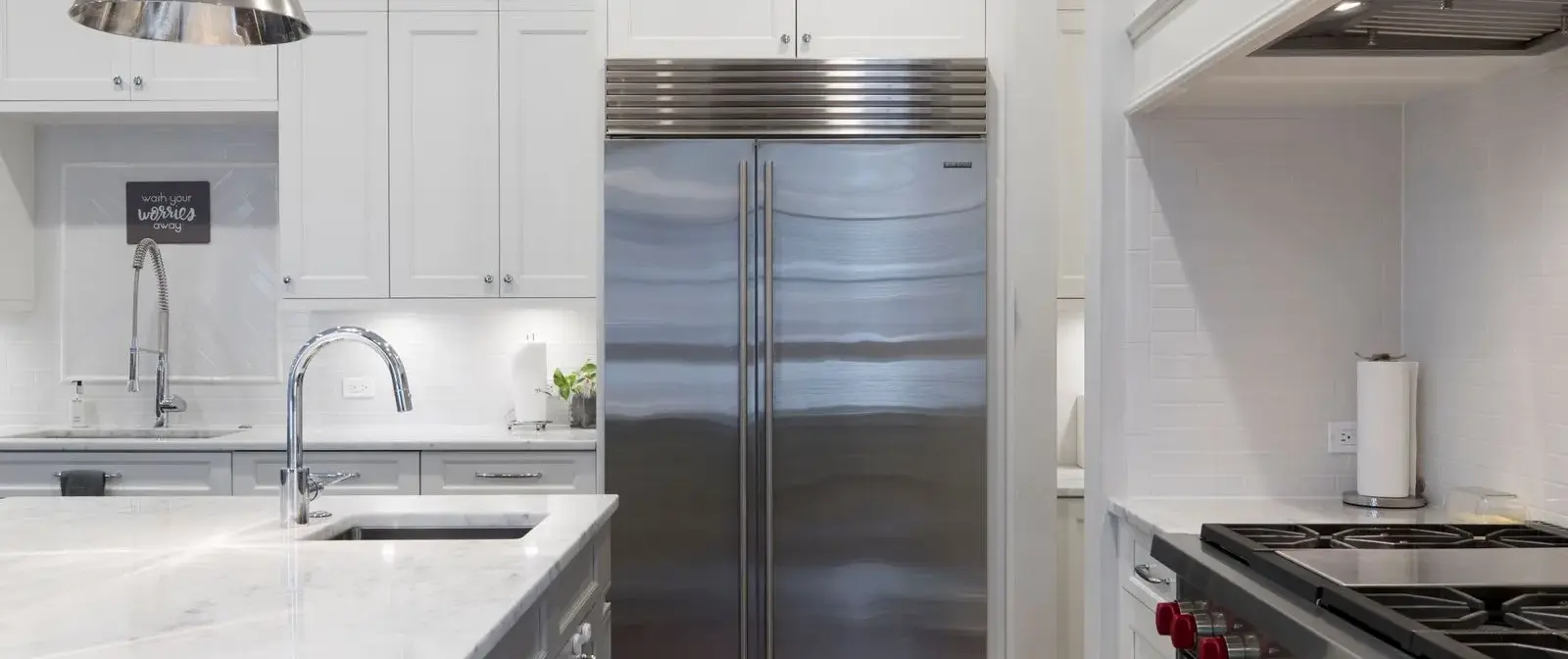 Stainless steel refrigerator beside white kitchen cabinets
